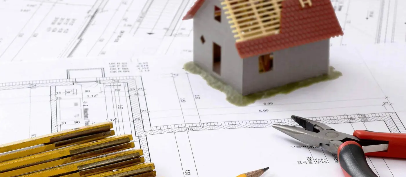 Bauplan mit Gebäudemodell und Zeichenwerkzeug